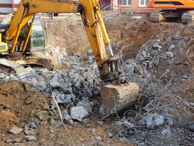 İnşaat işi, sökülüyor. Endüstriyel hidrolik çekiç kullanılarak güçlendirilmiş beton yapıların profesyonel yıkımı. Metal alaşımlı çubuklar. Beton enkazı ve kırıntıları.