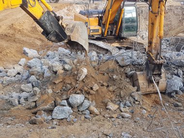 İnşaat işi, sökülüyor. Endüstriyel hidrolik çekiç kullanılarak güçlendirilmiş beton yapıların profesyonel yıkımı. Metal alaşımlı çubuklar. Beton enkazı ve kırıntıları.