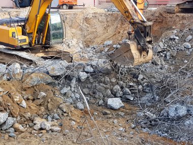 İnşaat işi, sökülüyor. Endüstriyel hidrolik çekiç kullanılarak güçlendirilmiş beton yapıların profesyonel yıkımı. Metal alaşımlı çubuklar. Beton enkazı ve kırıntıları.