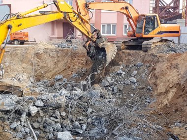İnşaat işi, sökülüyor. Endüstriyel hidrolik çekiç kullanılarak güçlendirilmiş beton yapıların profesyonel yıkımı. Metal alaşımlı çubuklar. Beton enkazı ve kırıntıları.