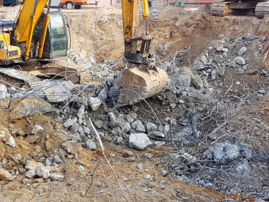 İnşaat işi, sökülüyor. Endüstriyel hidrolik çekiç kullanılarak güçlendirilmiş beton yapıların profesyonel yıkımı. Metal alaşımlı çubuklar. Beton enkazı ve kırıntıları.