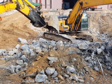 İnşaat işi, sökülüyor. Endüstriyel hidrolik çekiç kullanılarak güçlendirilmiş beton yapıların profesyonel yıkımı. Metal alaşımlı çubuklar. Beton enkazı ve kırıntıları.