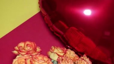 A heart-shaped balloon and a huge bouquet of orange roses are floating in the air. Romantic evening. Surprise for a loved one. The concept of love and romance.