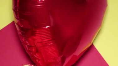 A heart-shaped balloon and a huge bouquet of orange roses are floating in the air. Romantic evening. Surprise for a loved one. The concept of love and romance.