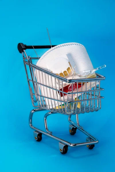 Cart from the store with a medical mask and medicines. The concept of the viral crisis. Close-up. Blue vertical background.