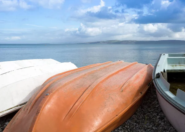 Barche rovesciate su una spiaggia rocciosa — Foto Stock