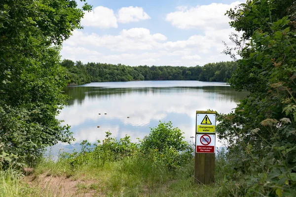 Deep lake with no swimming warning sign — Stock Photo, Image