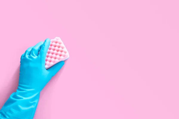 Hand i blått gummi handske hålla rosa rengöring svamp isolerad på rosa bakgrund med kopia utrymme för text eller logotyp — Stockfoto