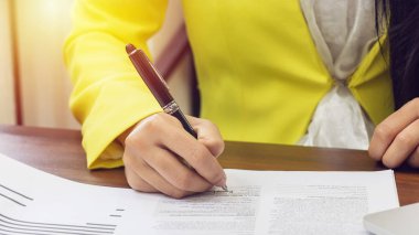 Sarı süitteki iş kadınları sözleşme belgesinde onay belgesini kalem ile imzalıyorlar. İş ortaklığı ve avukat konsepti hukuki anlaşması