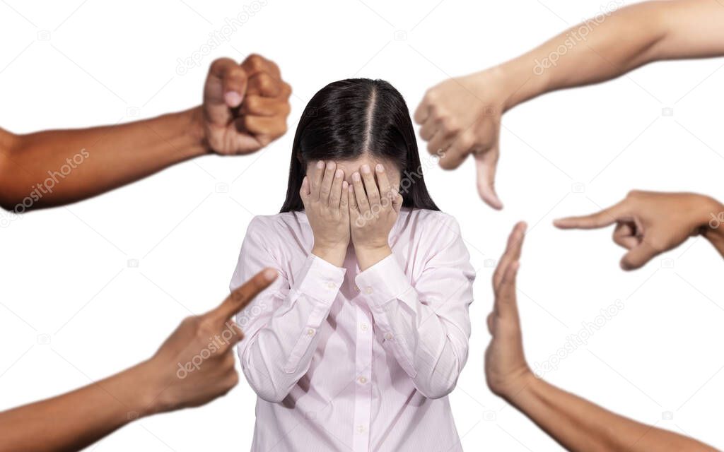 woman covered her face with regret for being bullying , sexism , racism and hate surrounded by hands mocking her, scoffing with offended at social of workplace 