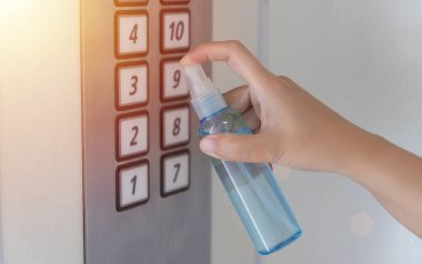 Dezenfekte, sterilize etme, hijyen bakımı. Asansör düğmesinde alkol spreyi kullanan ve temizlik ve dezenfeksiyon için sık sık temas edilen insanlar COVID-19 enfeksiyonları sırasında yayılan mikropların önlenmesi