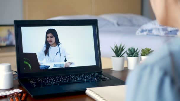 病気の女性はビデオ会議を利用しノートパソコンで医師とオンライン相談し患者はビデオ通話で病気や薬について医師に尋ねます テレヘルス テレメディシン オンライン病院 — ストック動画