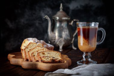 Sütlü bir fincan kahve ve ahşap masada kuru üzümlü kek.