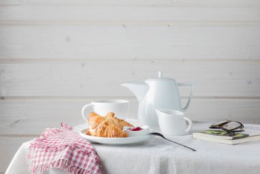 Kahvaltınız kahve, kruvasan ve reçel beyaz masada.