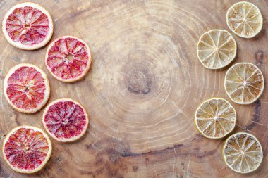 Dried red oranges, limes and lemons on wooden background with copy space