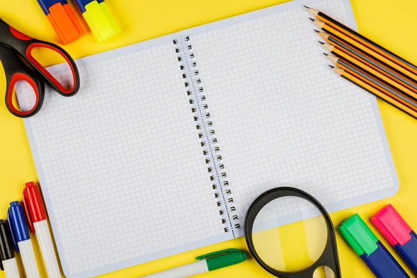 Back to school. School supplies on yellow background. Calculator, scissors, pen, notebook isolated on yellow.