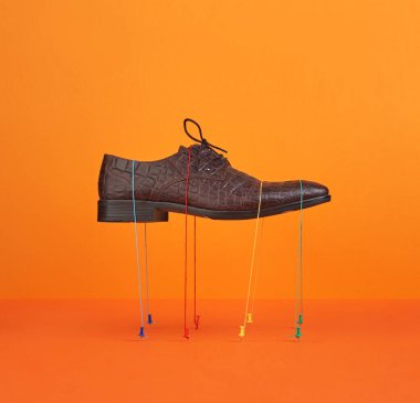 Havada süzülen kahverengi timsah derisi ayakkabılar fotokopi alanı için turuncu arka plan.