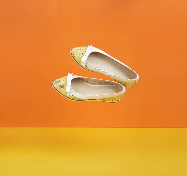Un par de zapatos amarillos voladores de verano sobre un fondo amarillo-naranja para una pancarta . —  Fotos de Stock
