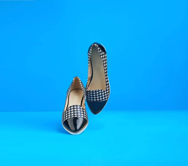 pair of dancing summer black and white female shoes on a blue background.