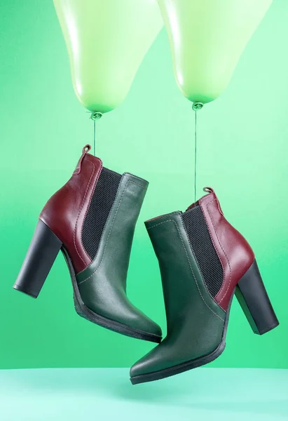 Egy pár zöld és piros őszi bőr női cipő lóg zöld lufik a zöld háttér — Stock Fotó