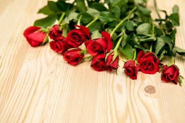 Kırmızı güller ahşap bir masanın üzerinde toplu kartpostalla, Aşıkların Günü 'ne kadar uzanır, 8 Mart' a kadar.