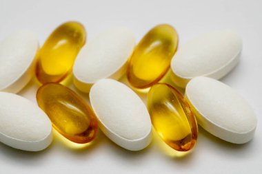 Beyaz arka planda Omega 3 Omega 6 kalsiyum D3 vitaminleri. Diyet ve sağlıklı beslenme için yağlı kapsüller.