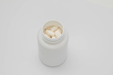 Beyaz yuvarlak kaplamalı tabletler plastik bir kutudan onlarla birlikte dağılmış. Uyuşturucu, hap..