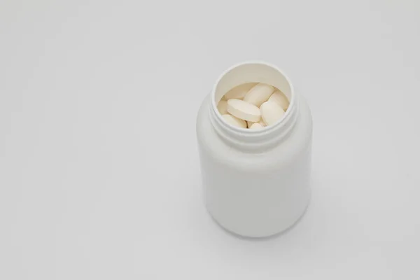 White round tablets covered with a cover are scattered from a plastic can with them. Drugs, pill. — Stock Photo, Image