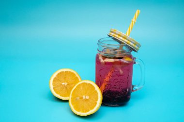 Mavi arka planda kepi olan bir bardakta ferahlatıcı bir limon ve dut içeceği. Meyve taze limonata.