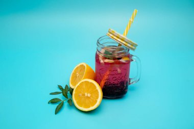 Mavi arka planda kepi olan bir bardakta ferahlatıcı bir limon ve dut içeceği. Meyve taze limonata.