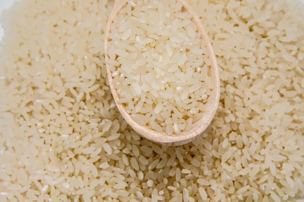 White rice with a wooden spoon on a pile of rice on the white background Jasmine rice for cooking.