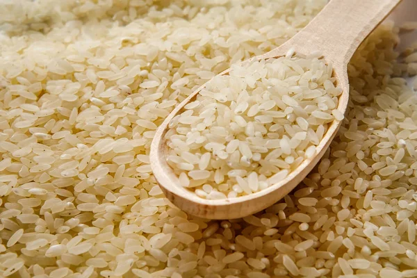 White rice with a wooden spoon on a pile of rice on the white background Jasmine rice for cooking.