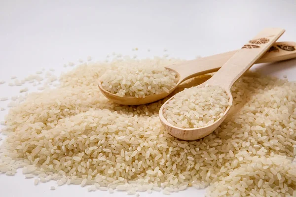White rice with a wooden spoon on a pile of rice on the white background Jasmine rice for cooking.