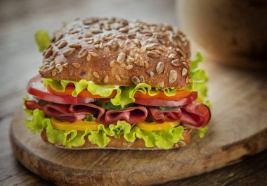 Ahşap masada jambonlu ve peynirli sandviç.