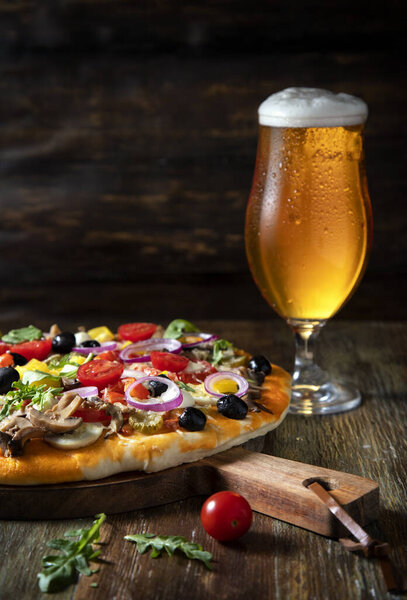 Pizza and glass of beer on a wooden table