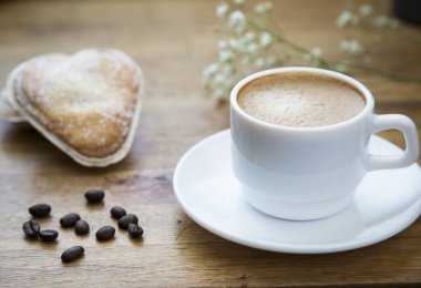 Sütlü kahve ve ahşap masada taze hamur işleri.