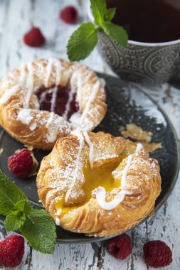 Tabakta taze hamur işleri ve ahşap bir masada ahududu.