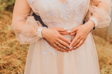 Kalp şeklinde bir karın üzerinde el ele tutuşan iki yeni evli. Düğün günü. Kırpılmış çerçeve