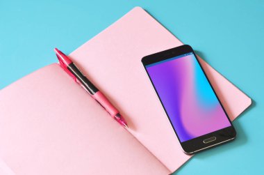 Soyut holografik akışına sahip akıllı telefon ekranda, pembe defter mavi masada. Tasarım için hazırlan