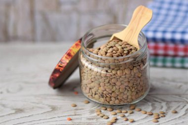 Cam kavanozdaki ahşap masada yeşil mercimek.