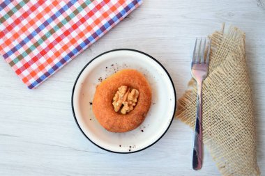 Kahvaltıda pastanın üst köşesi beyaz ahşap arka planda tabakta.