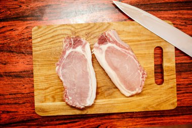 Çiğ domuz eti biftek kesme tahtası üzerinde baharatlar ile