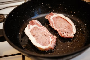 Çiğ domuz eti biftek ile bir tavada yemek yemek, ev mutfak, baharat