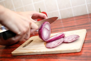 Kadının el kesme tahtası üzerinde kırmızı soğan kesmek