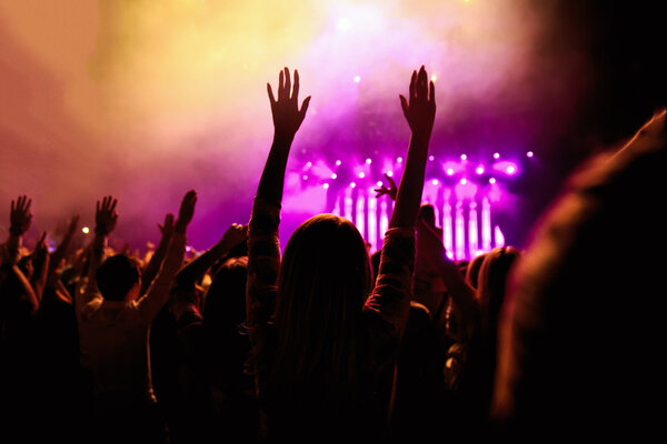 silhouettes of concert crowd in front on bright stage lights