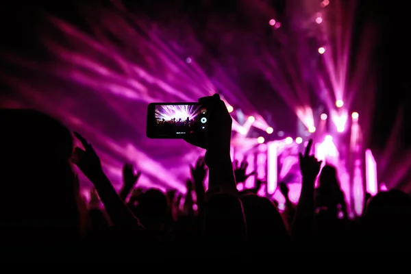 Hand with a smartphone records live music festival, Taking photo of concert stage