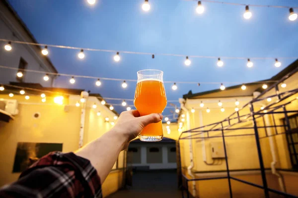 Bier in een glas in zijn hand, verlicht door lantaarns — Stockfoto