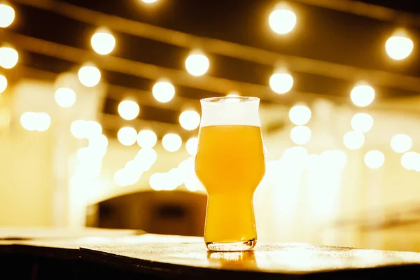 Um copo de cerveja de embalagem no fundo das lanternas — Fotografia de Stock