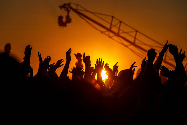 Hands up at sunset, Open air view Silhouettes of the summer festival. The light of a sun.