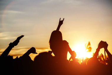 Yaz müzik festivalinde konser sırasında elleri havada dans eden, şarkı söyleyen ve müzik dinleyen kızlar.